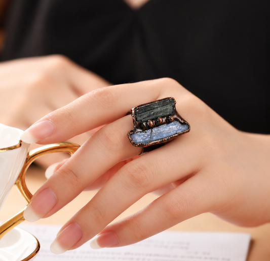 Woman wearing a green tourmaline and blue kyanite statement ring on her middle finger, with contrasting green and blue stones.