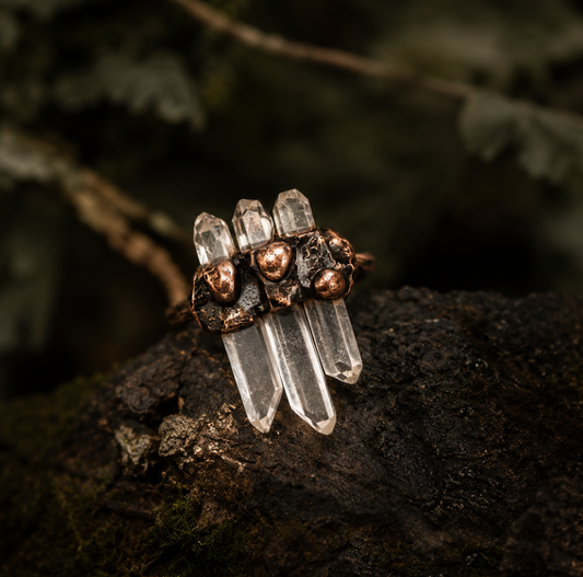 White crystal ring styled on natural stone with earthy moss, copper details, and clear quartz points.