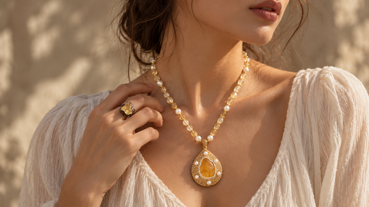 Woman wearing a honey-yellow citrine and pearl necklace with a raw citrine statement ring in warm natural light