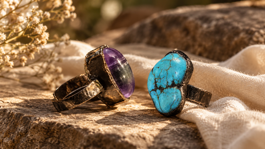 Amethyst and turquoise statement rings styled on warm stone with soft ivory fabric in natural sunlight