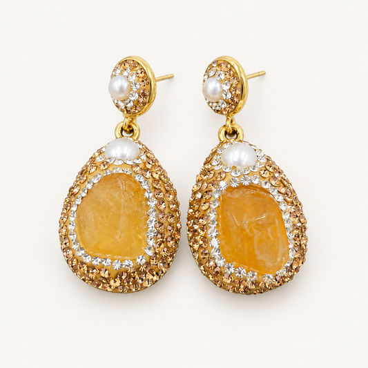 Gold-tone teardrop earrings with honey-yellow centers and white pearl accents, shown as a pair on an off-white background.
