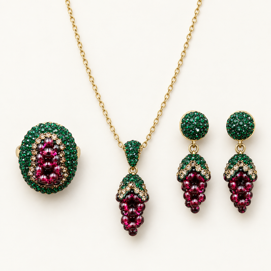 Garnet jewelry set with a grape-cluster oval ring, pendant necklace and drop earrings on an off-white background