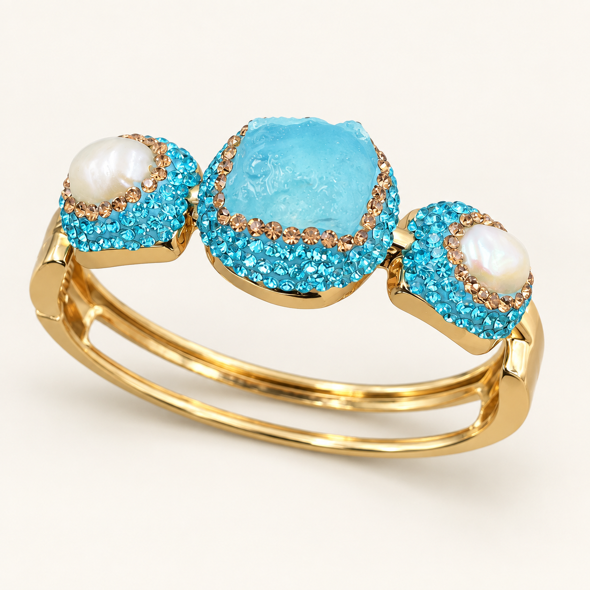 Turquoise bracelet with a raw stone center, freshwater pearl accents and twin gold-tone bands on an off-white background.