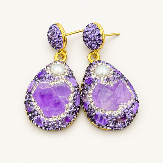 Purple earrings with teardrop pendants, white accents and gold-tone details on an off-white background.

