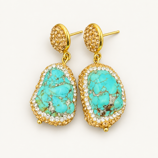 Turquoise drop earrings with irregular raw blue-green stones, Czech crystal borders and gold-tone tops on an off-white background.