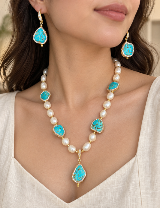 Woman wearing coastal turquoise necklace and asymmetric drop earrings with baroque pearls