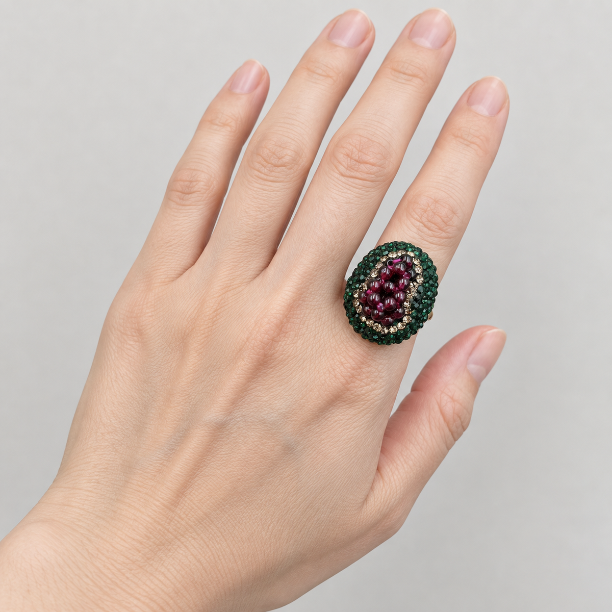 Oval garnet ring worn on an index finger, with the full hand visible to show its relative proportions.