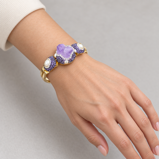 Amethyst bracelet worn on a wrist beside an ivory sleeve, showing the purple center stone and white side accents.