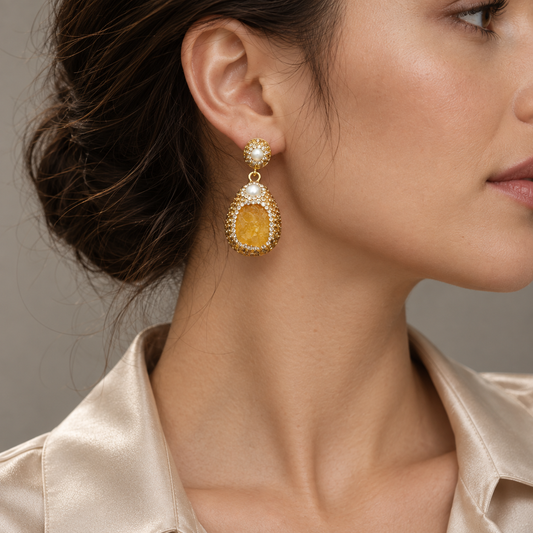 Citrine earrings in a close side view, showing a pearl-accented stud and a textured yellow drop below the earlobe.