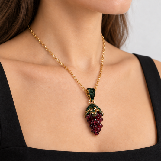 Angled close-up of a woman wearing a grape-cluster garnet necklace with a black square-neck top.