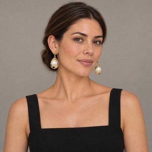 Model wearing baroque pearl earrings with a black square-neck dress and a low bun, showing both teardrop pendants.
