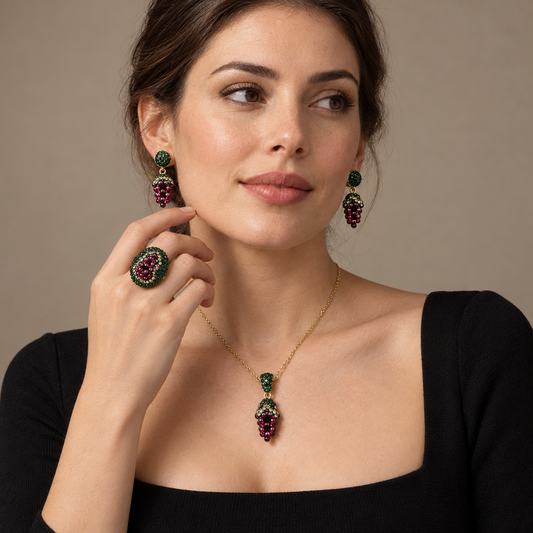 Woman in a black square-neck top wearing the garnet jewelry set with grape-cluster drop earrings, a pendant necklace and a matching oval ring.