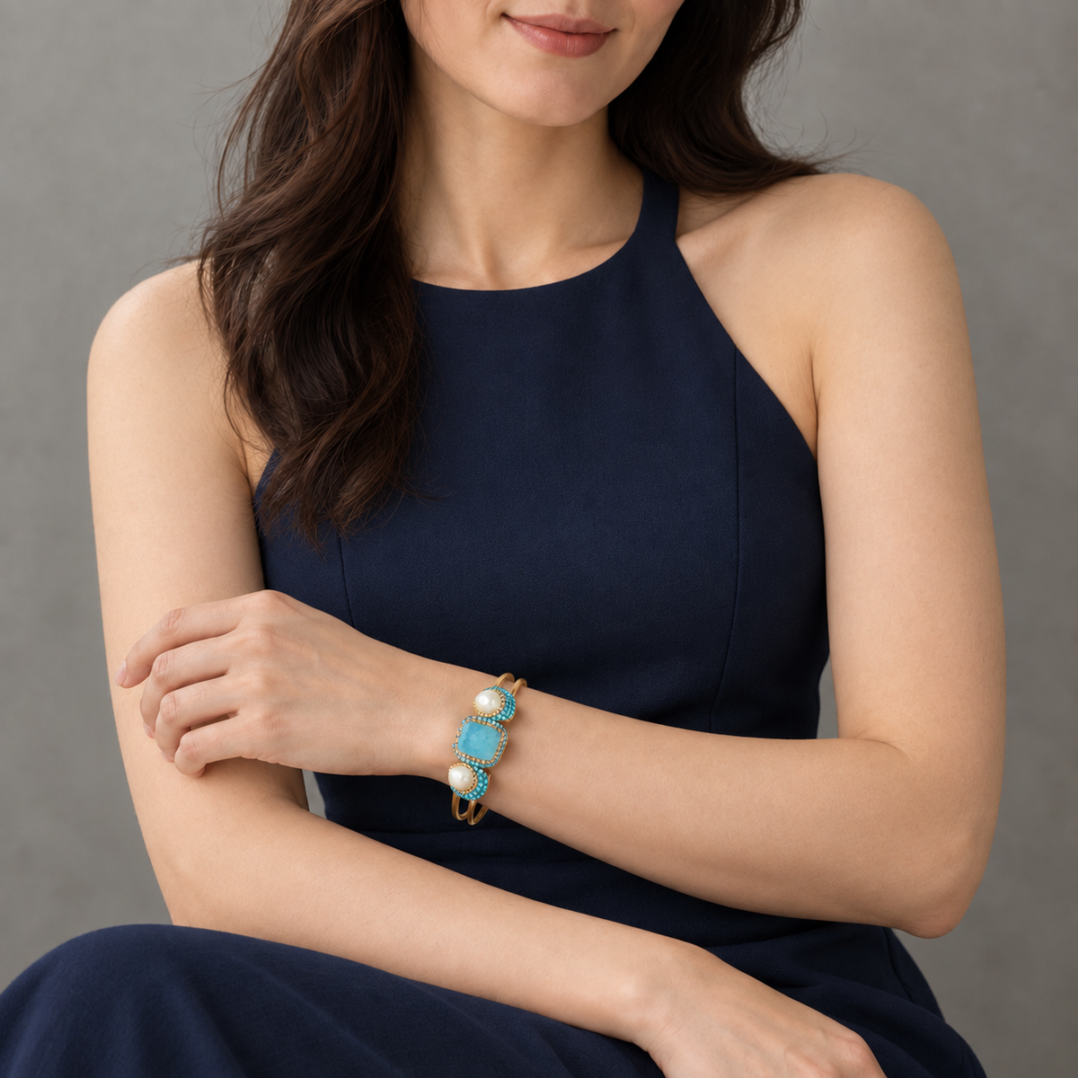 Turquoise bracelet with freshwater pearl accents worn with a sleeveless navy halter dress.