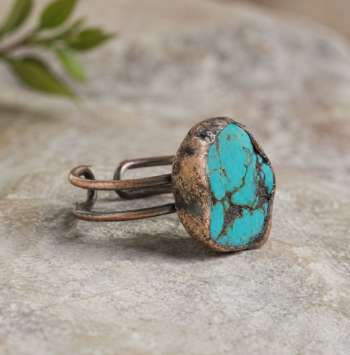 Turquoise ring with vivid blue-green stone, natural matrix pattern, and sculptural open-band design.