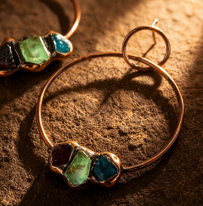 Blue apatite earrings with green fluorite and garnet accents, styled in warm natural light.