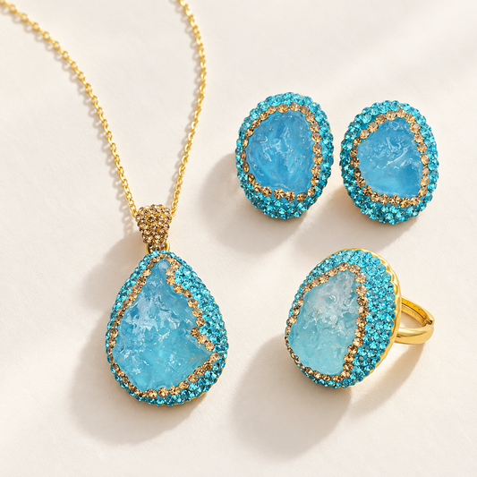 Raw aquamarine jewelry set with a pendant necklace, stud earrings and a statement ring on an off-white background.