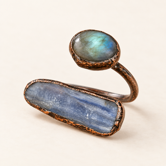 Labradorite ring with elongated raw blue kyanite in an asymmetrical open setting on an off-white background.