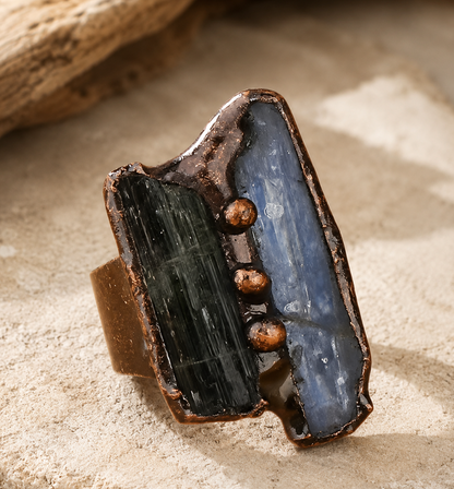 Green tourmaline ring with raw forest green stone, blue crystal accent, and rustic copper-tone setting.