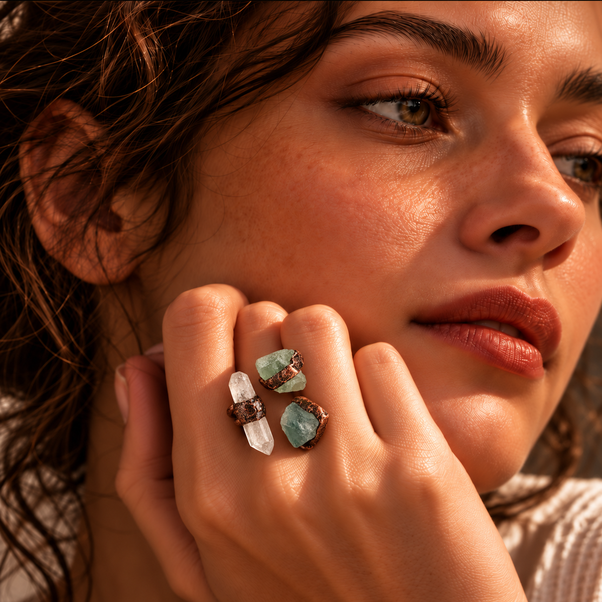 Close-up of a statement ring worn on the finger, showing clear quartz, green fluorite, and the open band.