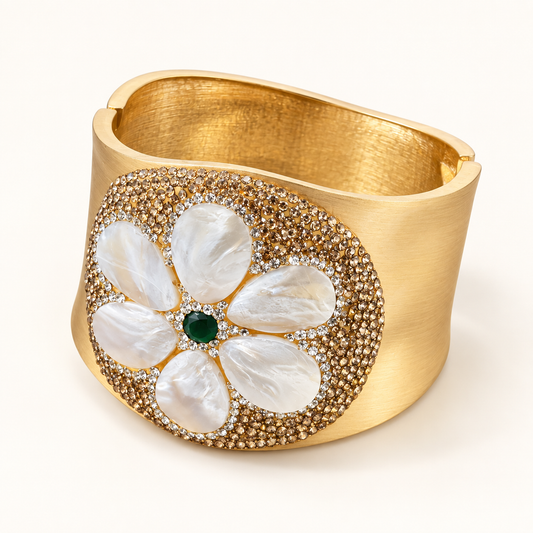 Mother-of-pearl bracelet with carved white flower petals, a deep green center and a wide gold-tone band on an off-white background.