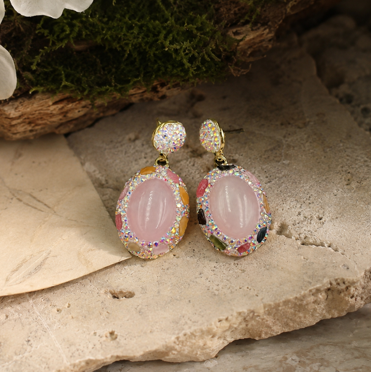 Elegant pink crystal earrings displayed on natural stone with romantic blush tones and refined feminine styling.