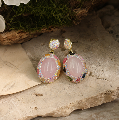 Elegant pink crystal earrings displayed on natural stone with romantic blush tones and refined feminine styling.