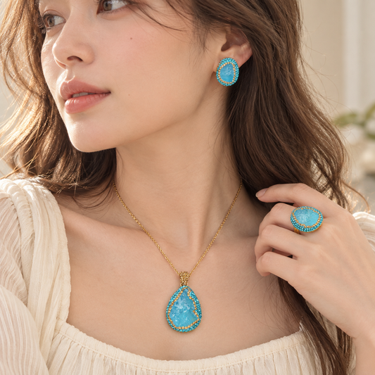 Model wearing blue aquamarine jewelry with pendant necklace, stud earrings and statement ring