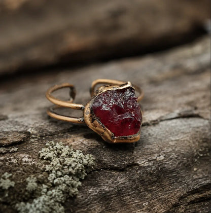 Garnet ring with deep red raw gemstone, organic edges, and vintage-inspired open-band design.