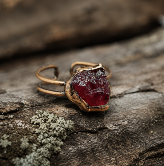 Garnet ring with deep red raw gemstone, organic edges, and vintage-inspired open-band design.