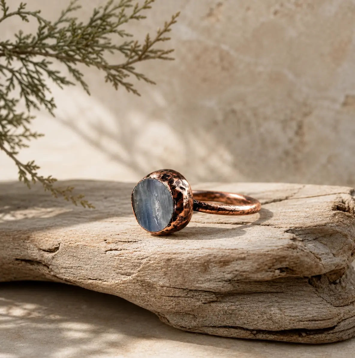 Kyanite ring displayed on weathered wood with a lake-blue crystal face and organic handcrafted texture.