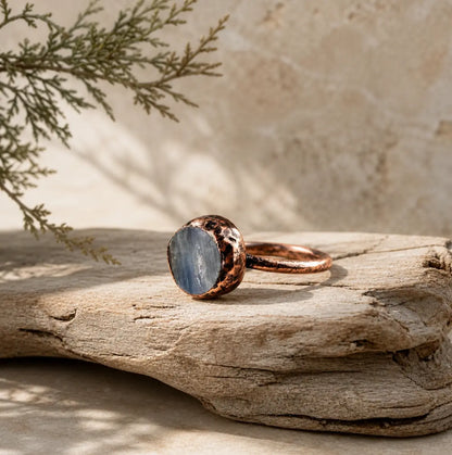 Kyanite ring displayed on weathered wood with a lake-blue crystal face and organic handcrafted texture.