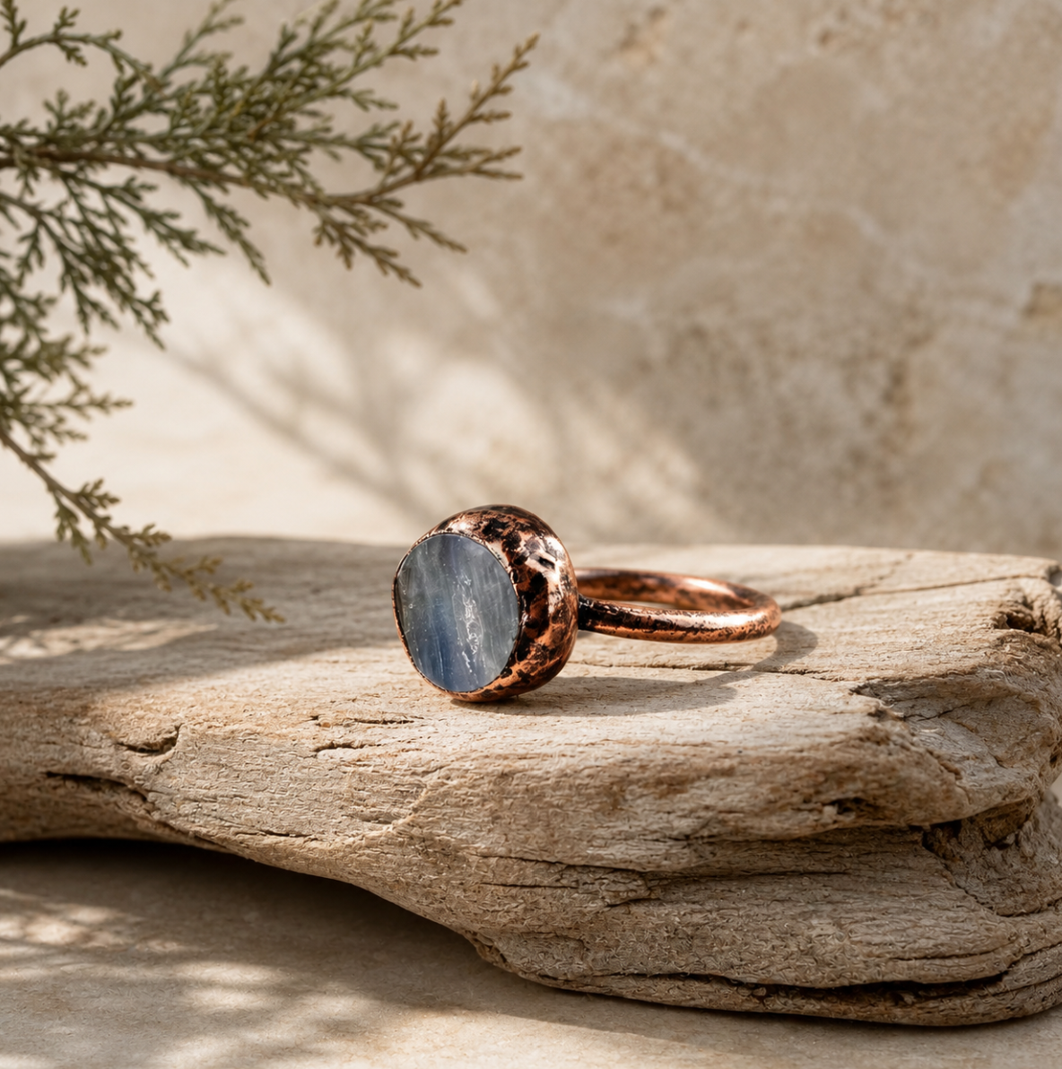 Kyanite ring displayed on weathered wood with a lake-blue crystal face and organic handcrafted texture.