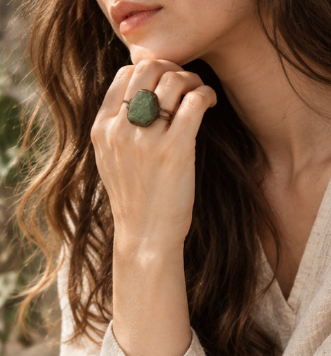 Macro view of a green apatite crystal ring, revealing the rough stone texture, irregular edges, and dark antiqued setting.