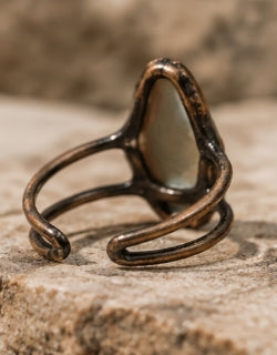 Close-up of a blue stone ring worn on the hand, showing the elongated moonstone and split open band