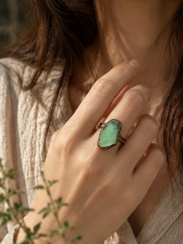 Green fluorite statement ring worn with neutral linen, showing its organic shape and soft green color