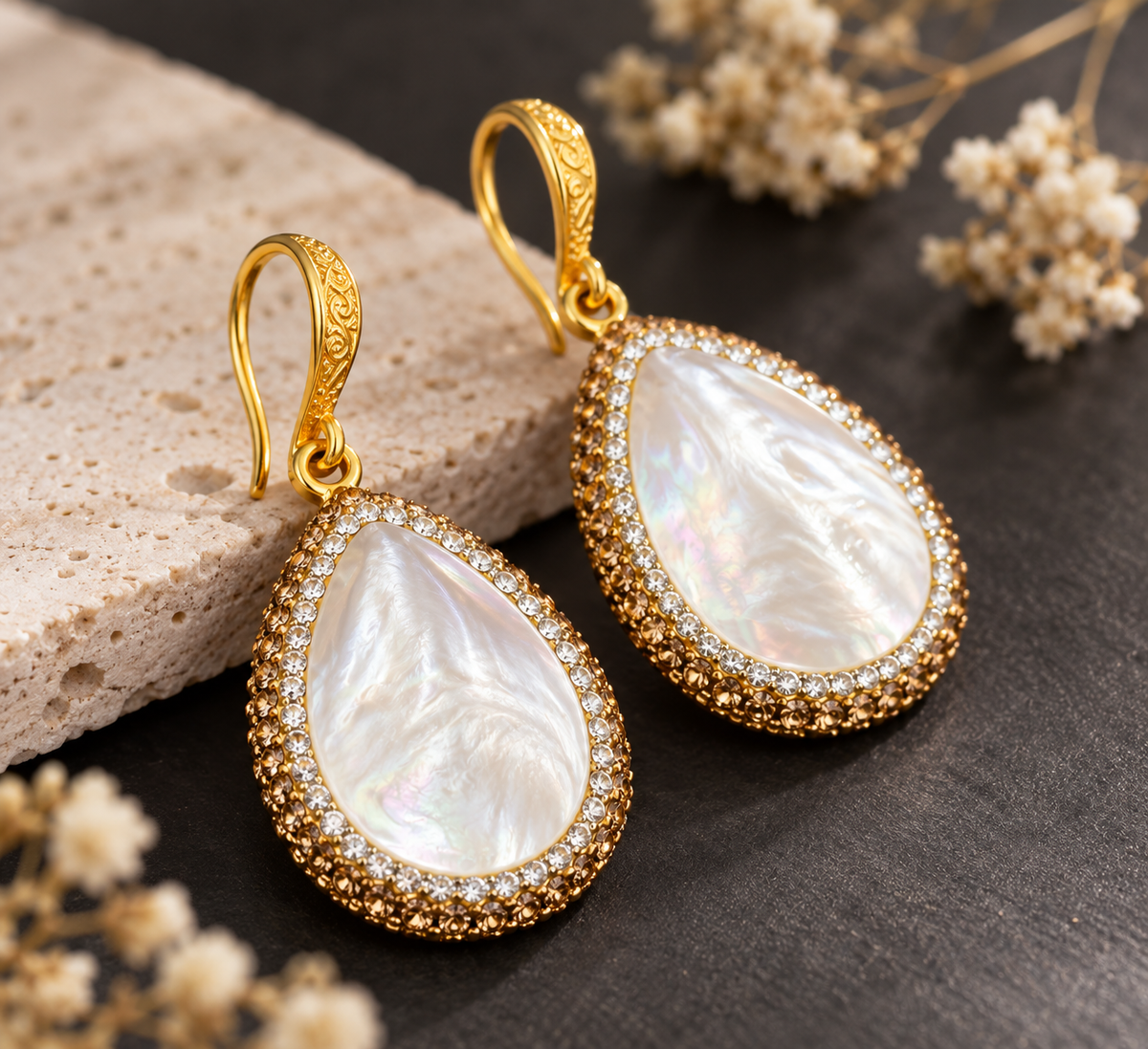 Close-up mother of pearl earrings showing iridescent white shell texture, gold-tone hooks and sparkling borders