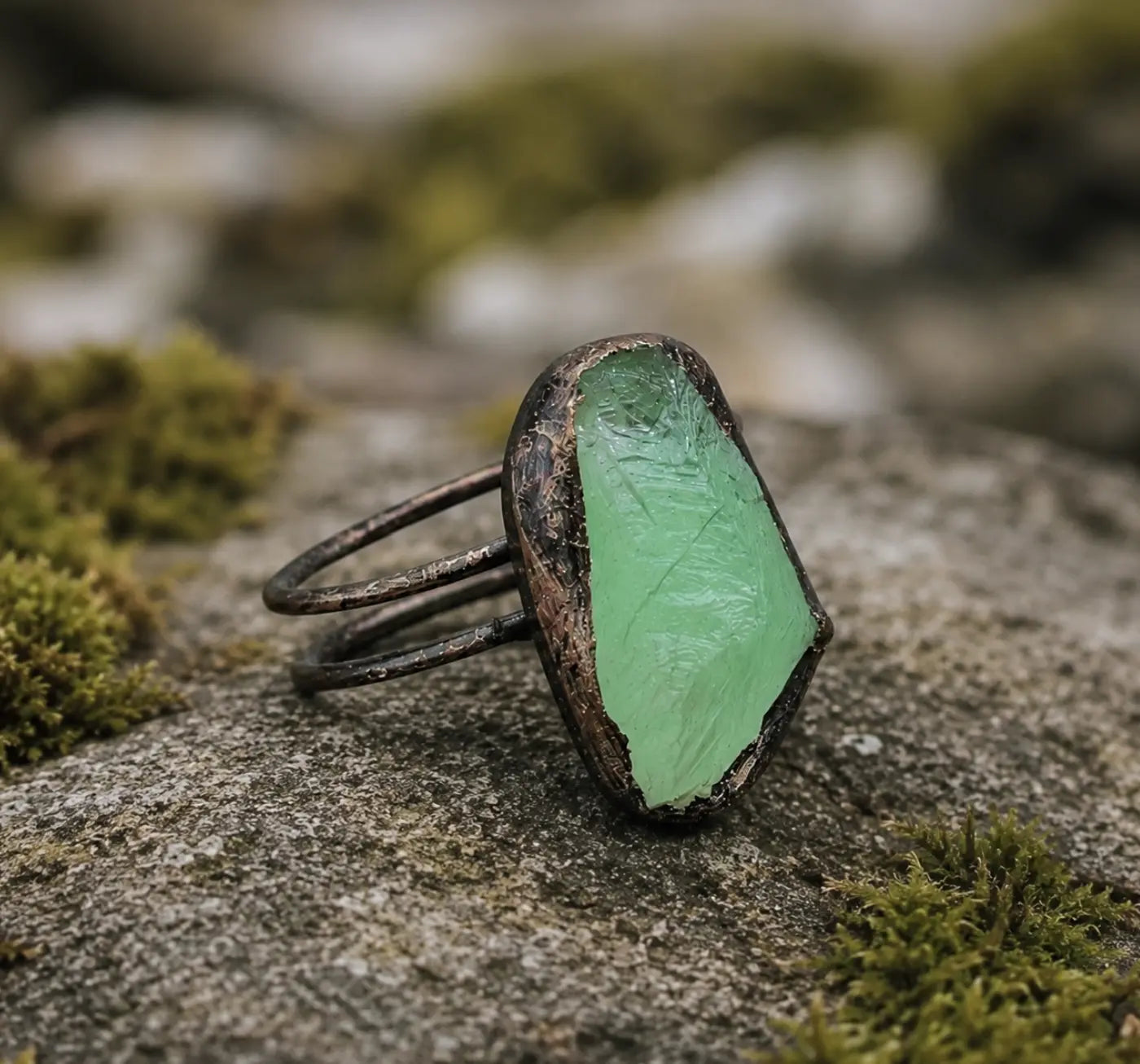 Fluorite ring displayed on mossy stone with soft green color and earthy crystal texture.
