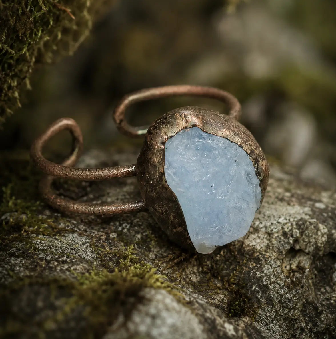 Aquamarine ring with soft ocean-blue stone, natural texture, and organic open-band design.