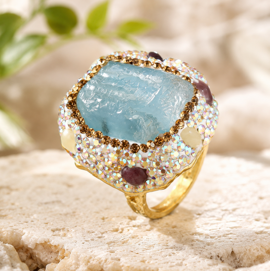 Elegant march birthstone jewelry featuring an ocean-blue crystal ring with soft gold details and light-catching stones.