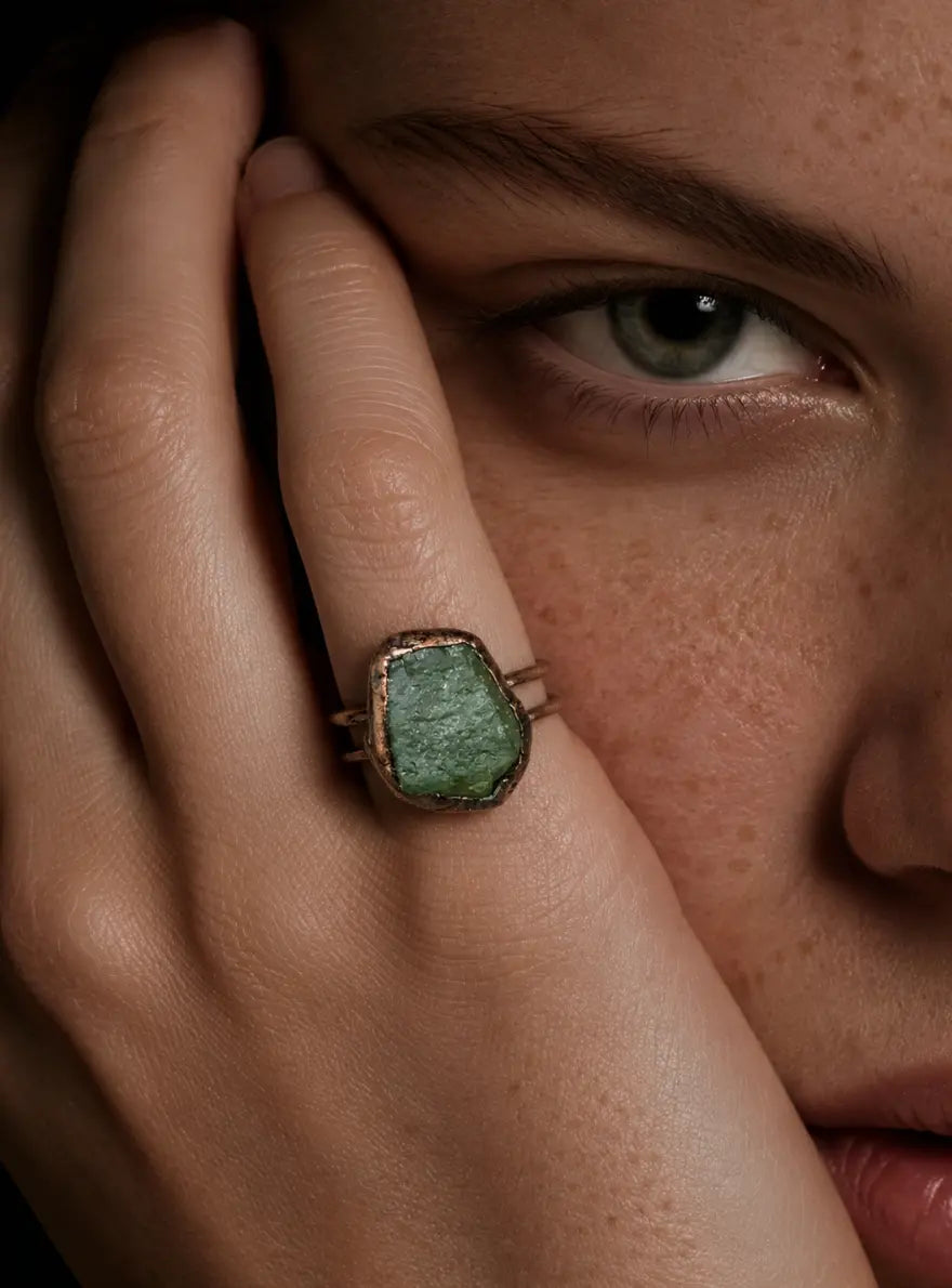 Green gemstone ring styled on the hand with organic mineral surface and quiet natural elegance.
