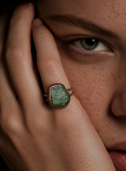 Green gemstone ring styled on the hand with organic mineral surface and quiet natural elegance.