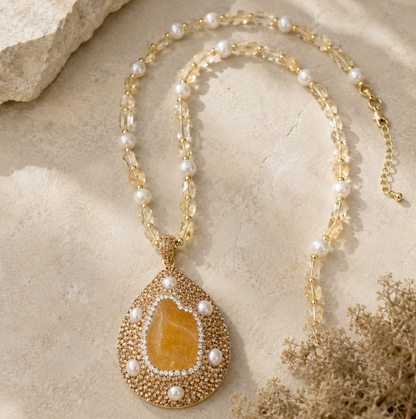 Citrine pendant jewelry styled on the neckline with warm light, soft fabric, and a refined feminine mood.