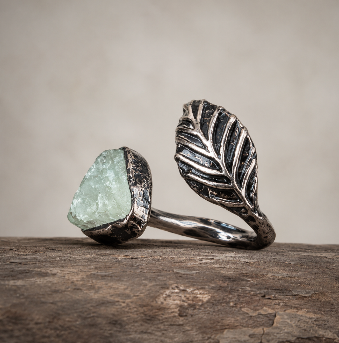 Green fluorite feather ring with pale green crystal, sculpted silver-tone feather, and rustic natural setting.
