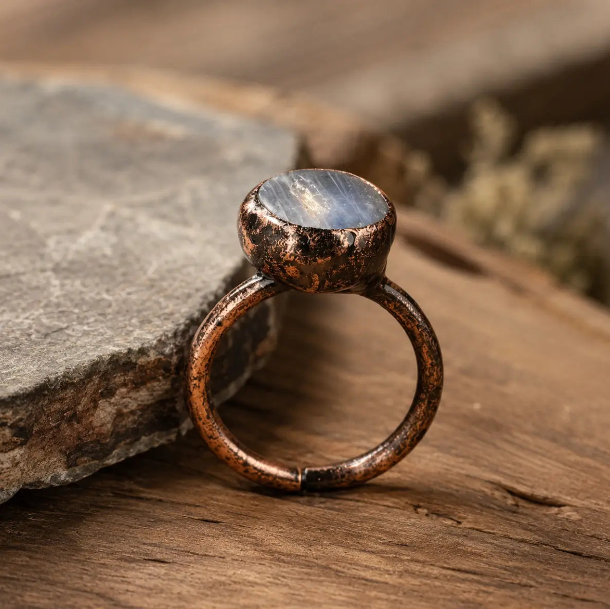 Blue kyanite ring with round flat gemstone, rustic metal setting, and soft natural styling.