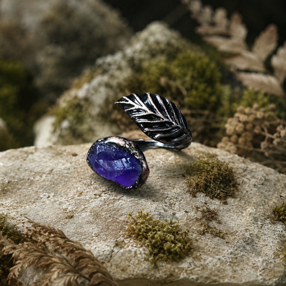 Purple feather ring featuring an amethyst gemstone, leaf-like feather shape, and woodland-inspired styling.
