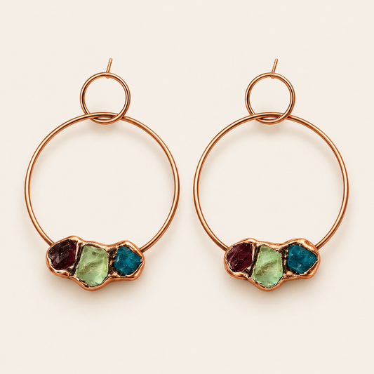 Pair of copper large hoop earrings with garnet, green fluorite, and blue apatite on warm off-white.