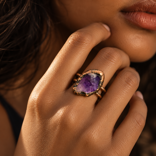 Amethyst ring worn on the hand, showing the real scale of the irregular purple stone and double-band design.