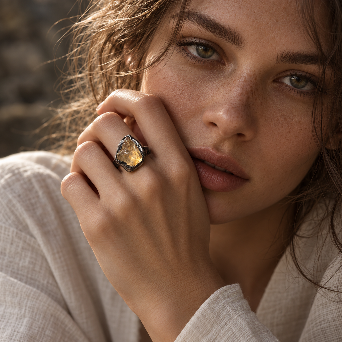Citrine ring worn in warm natural light, showing the golden stone as a sculptural focal point in a styled portrait.