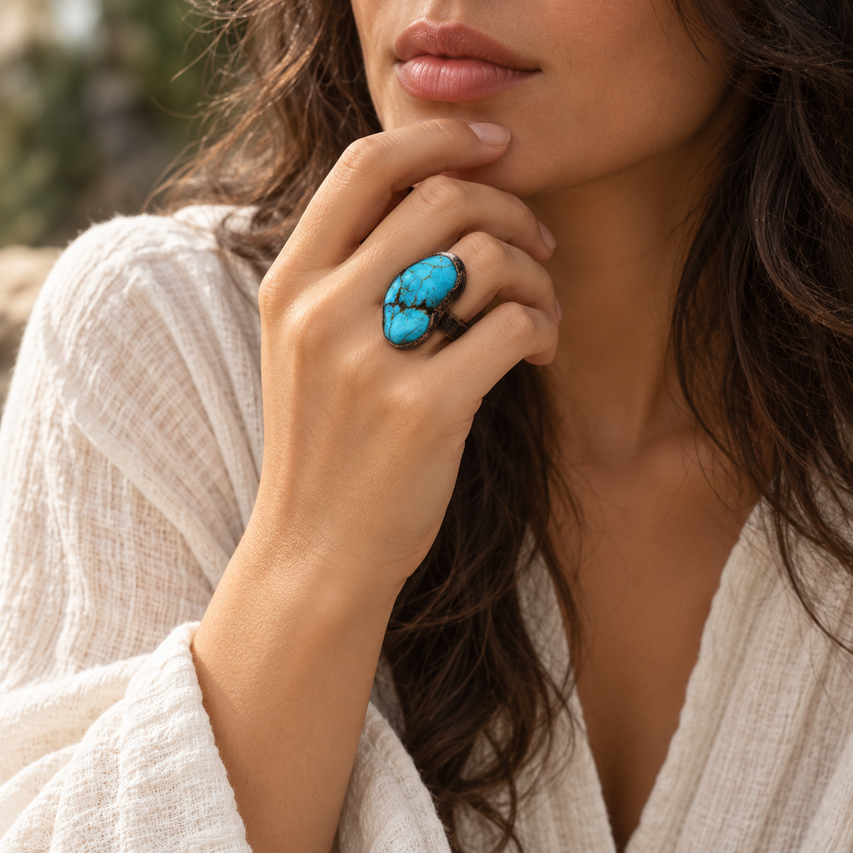 Turquoise ring worn with a neutral look, showing the vivid blue stone as a bold focal point in the overall styling.