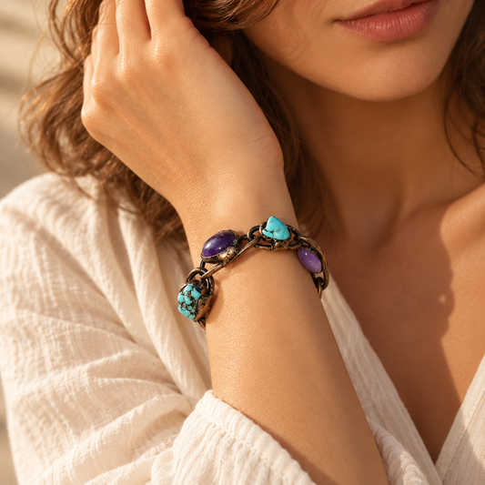 Woman wearing an amethyst and turquoise bracelet, with oval purple and blue-green stones arranged around the wrist.